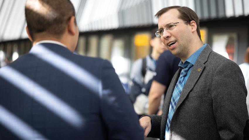 Georgia Tech OMSCS Executive Director David Joyner talking with a colleague during a seminar 